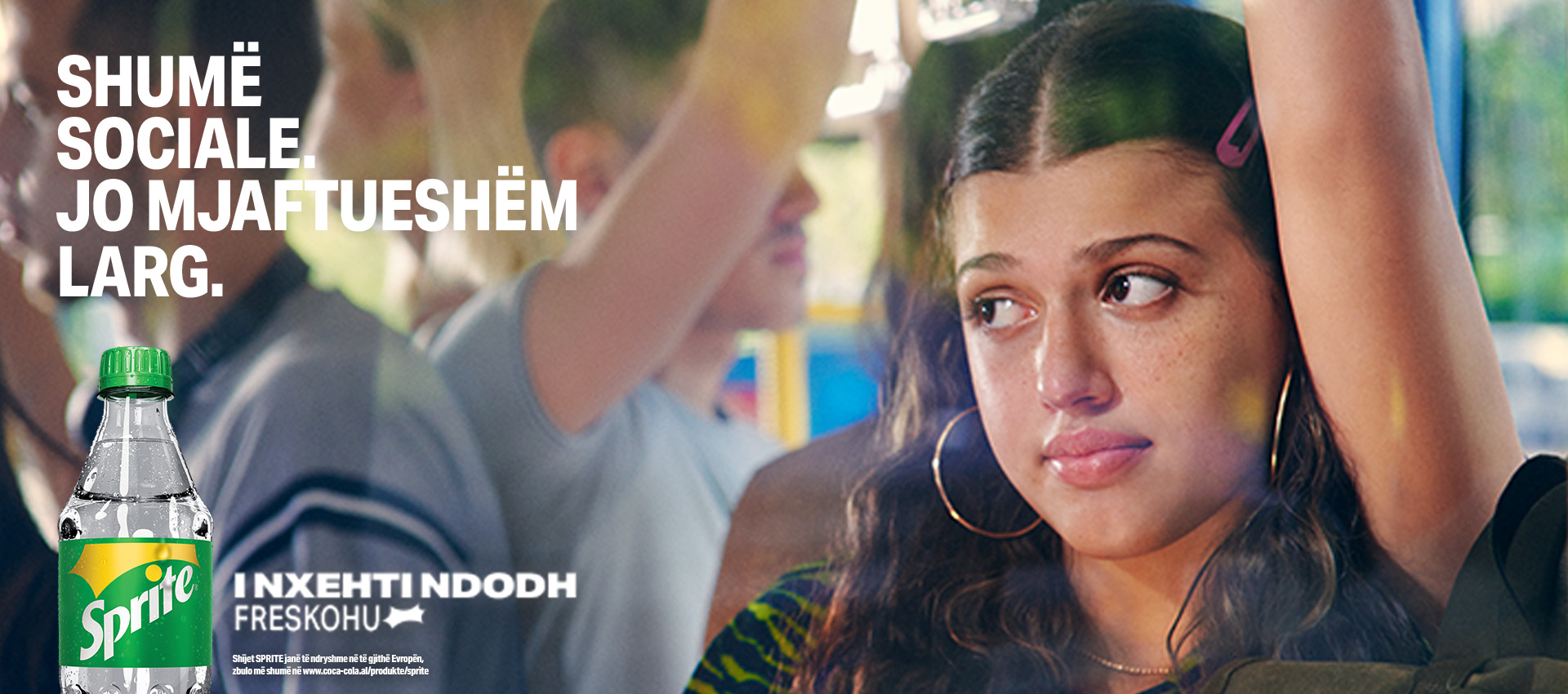 Një grua e re me shprehje të lodhur mes një turme. Një shishe Sprite në plan të parë. "Shumë sociale. Jo mjaftueshëm larg."