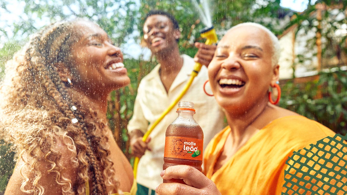 três pessoas se molhando com mangueira amarela tomando chas leao