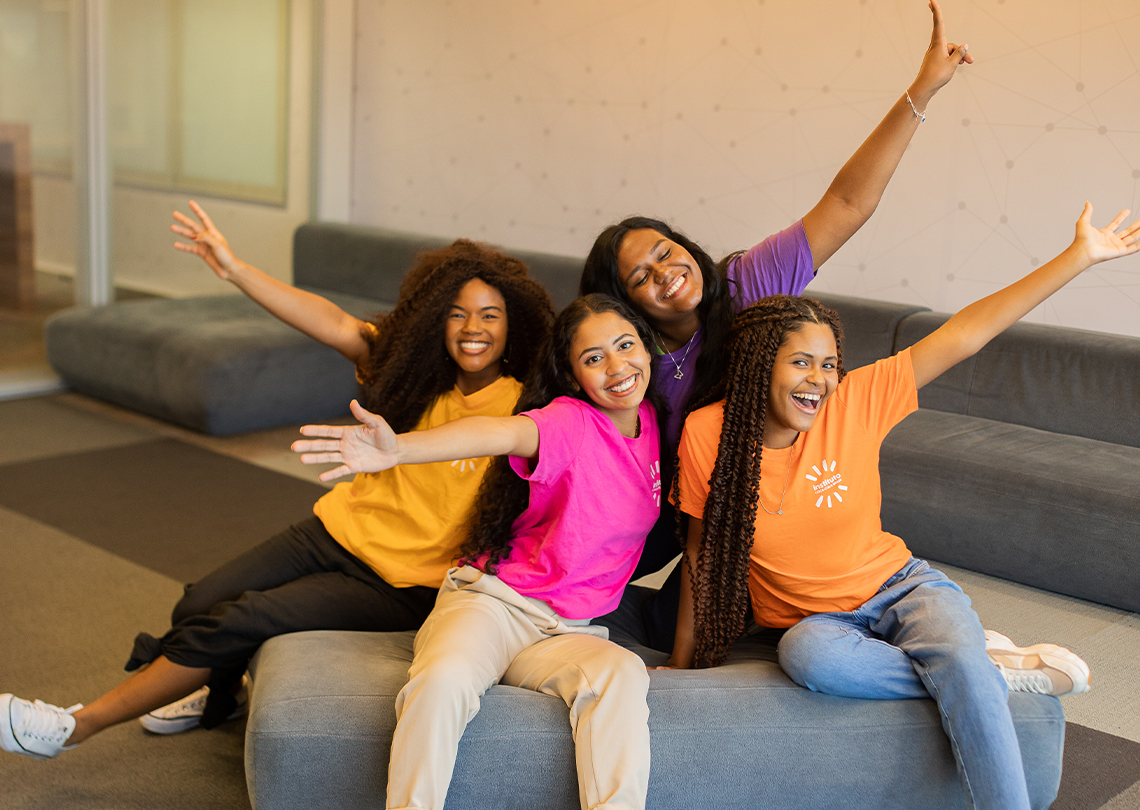 Grupo de meninas posando alegremente em camisetas coloridas.