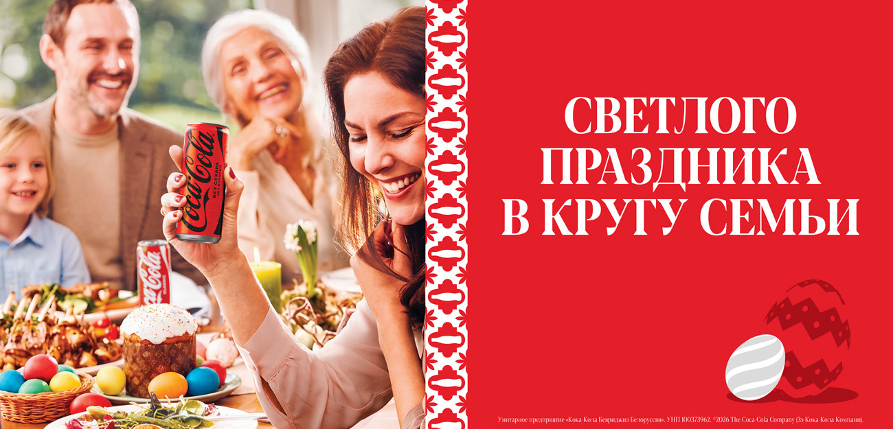 Рука ў касцюме Санты трымае бутэльку Coca-Cola на чырвоным фоне з навагоднім надпісам.