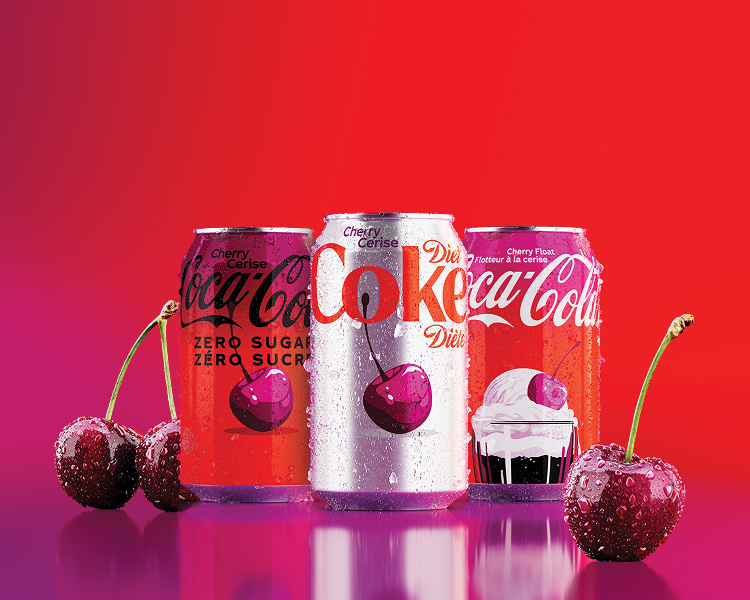 Three Coca-Cola cans with bilingual English/French labels — Cherry Coca-Cola Zero Sugar/Zéro sucre, Diet Coke Cherry/Cerise Diète, and Coca-Cola Cherry Float/Flotteur à la cerise — arranged against a red background with fresh cherries and water droplets on a reflective purple-pink surface.