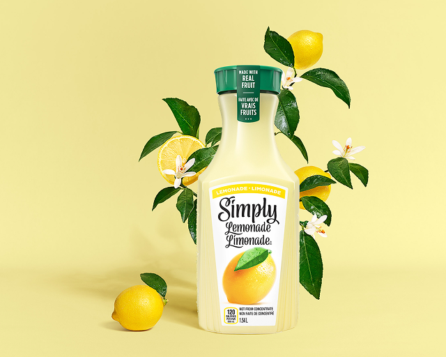 a carafe of simply lemonade on a leafy yellow background