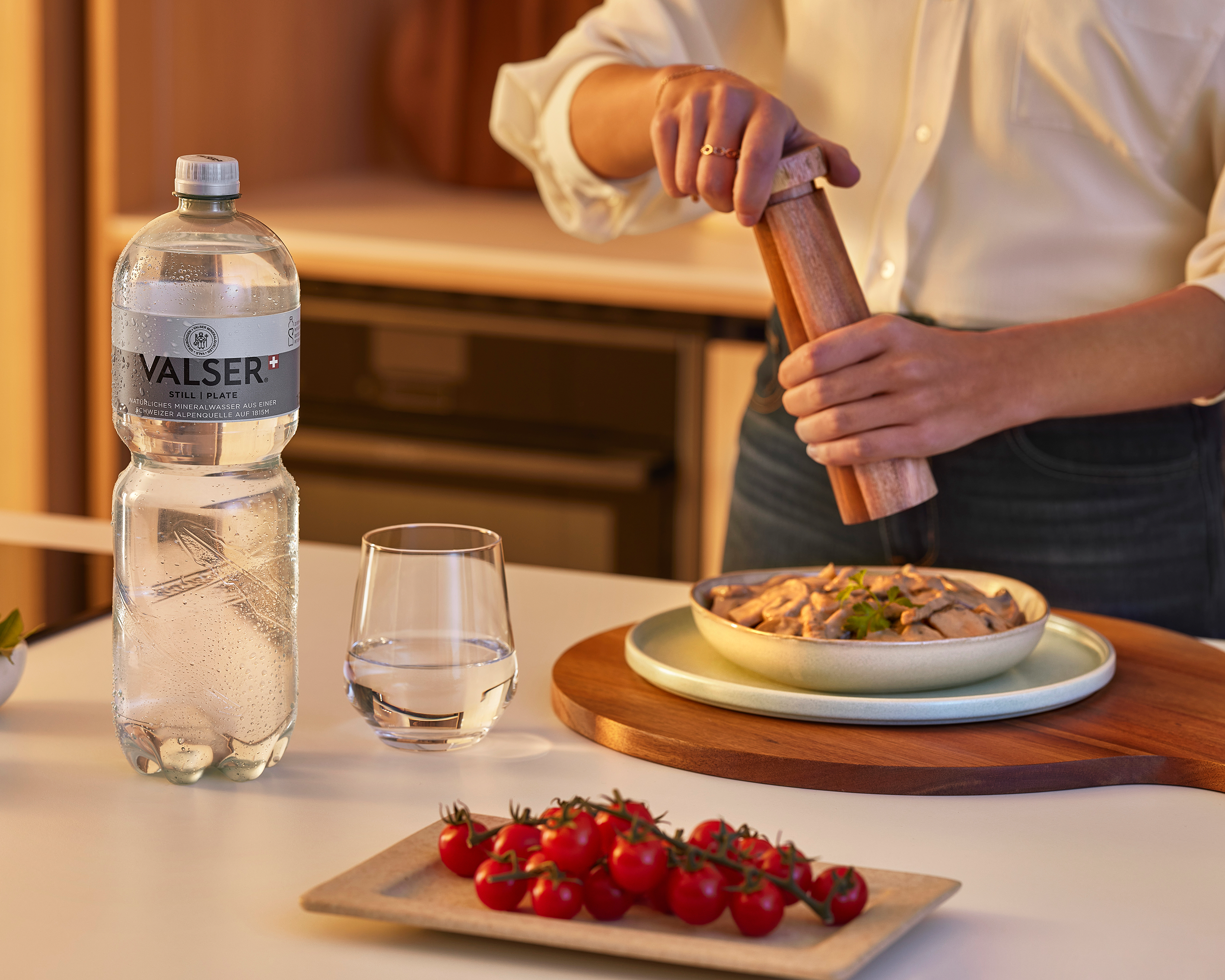 Bouteille Valser sur une table avec verre d’eau et assiette