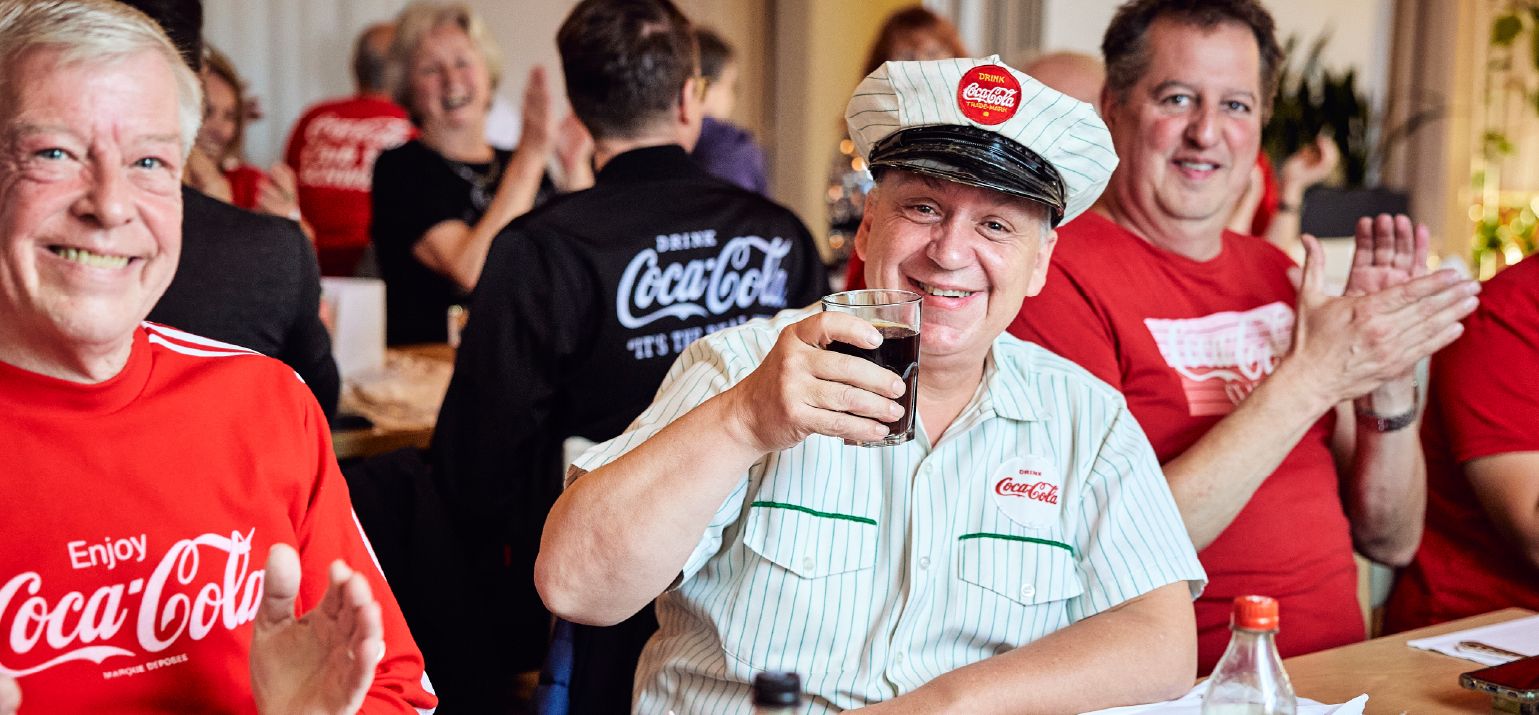 Männer in Kleidung mit dem Coca‑Cola‑Logo