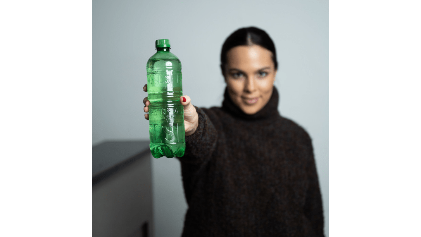 Femme tenant une bouteille verte de Valser sans étiquette