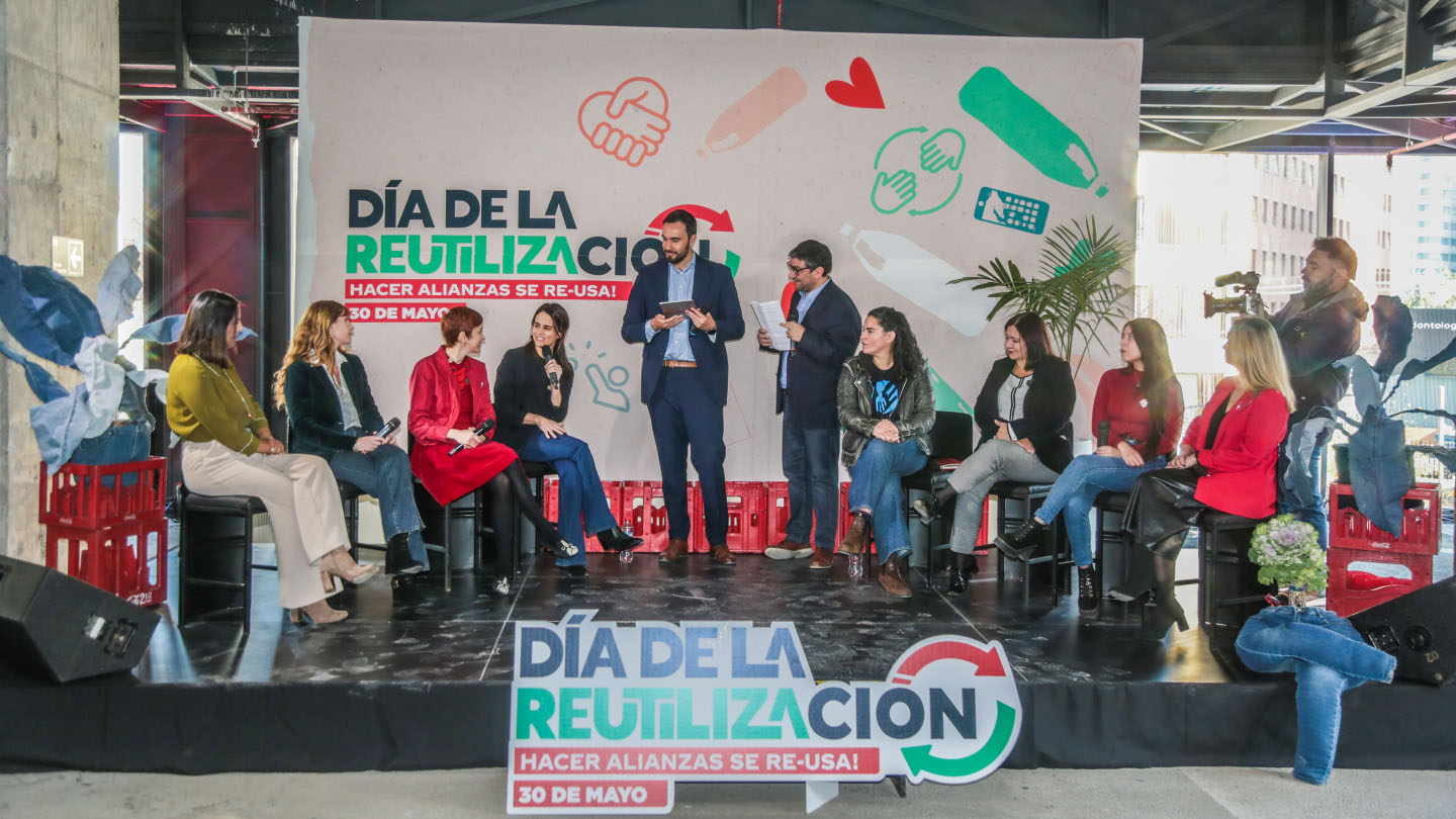 Grupo de personas sobre un escenario. Debajo, un cartel sobre el día de la reutilización.