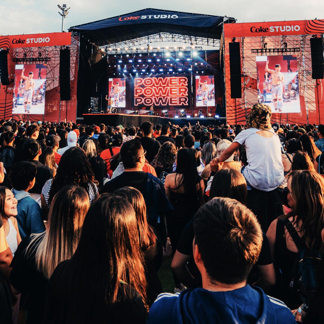 Multitud en un concierto de Coke Studio Chile, con el escenario iluminado y pantallas mostrando 'POWER' al fondo