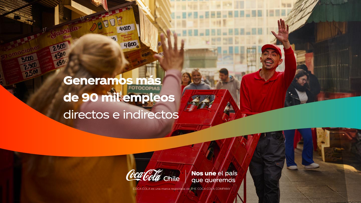 Hombre sonriente con polera roja de Coca-Cola levantando la mano a una mujer en la calle, con cajas de bebidas.