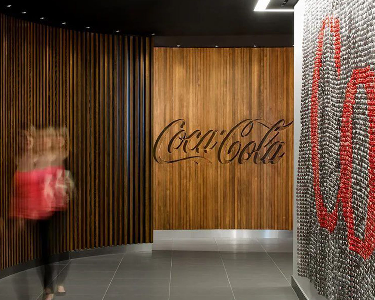 Interior de oficina de Coca-Cola con paredes de madera y una decoración moderna, destacando el logo de la marca.