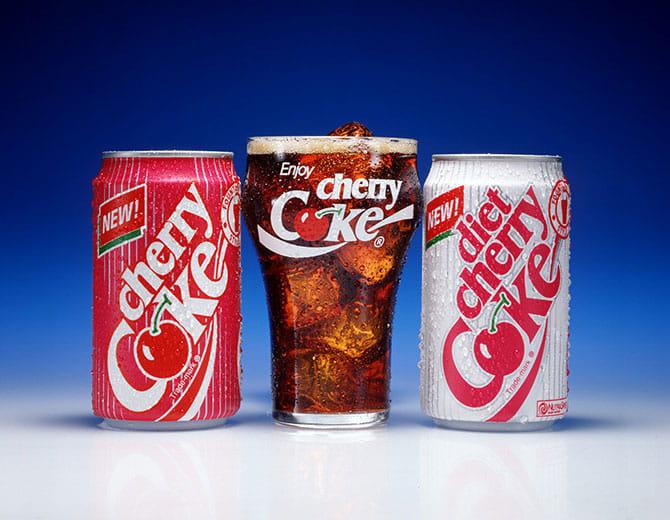 Cherry Coke purk, klaas jää ja Cherry Coke joogiga ning Diet Cherry Coke purk sinise tausta ees.