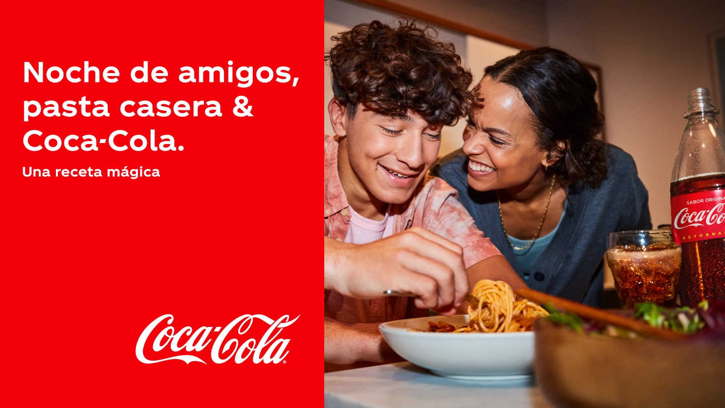 Dos amigos riendo mientras cenan spaghettis acompañado con una Coca-Cola. Texto: Noche de amigos, pasta casera & Coca-Cola. Una receta mágica.