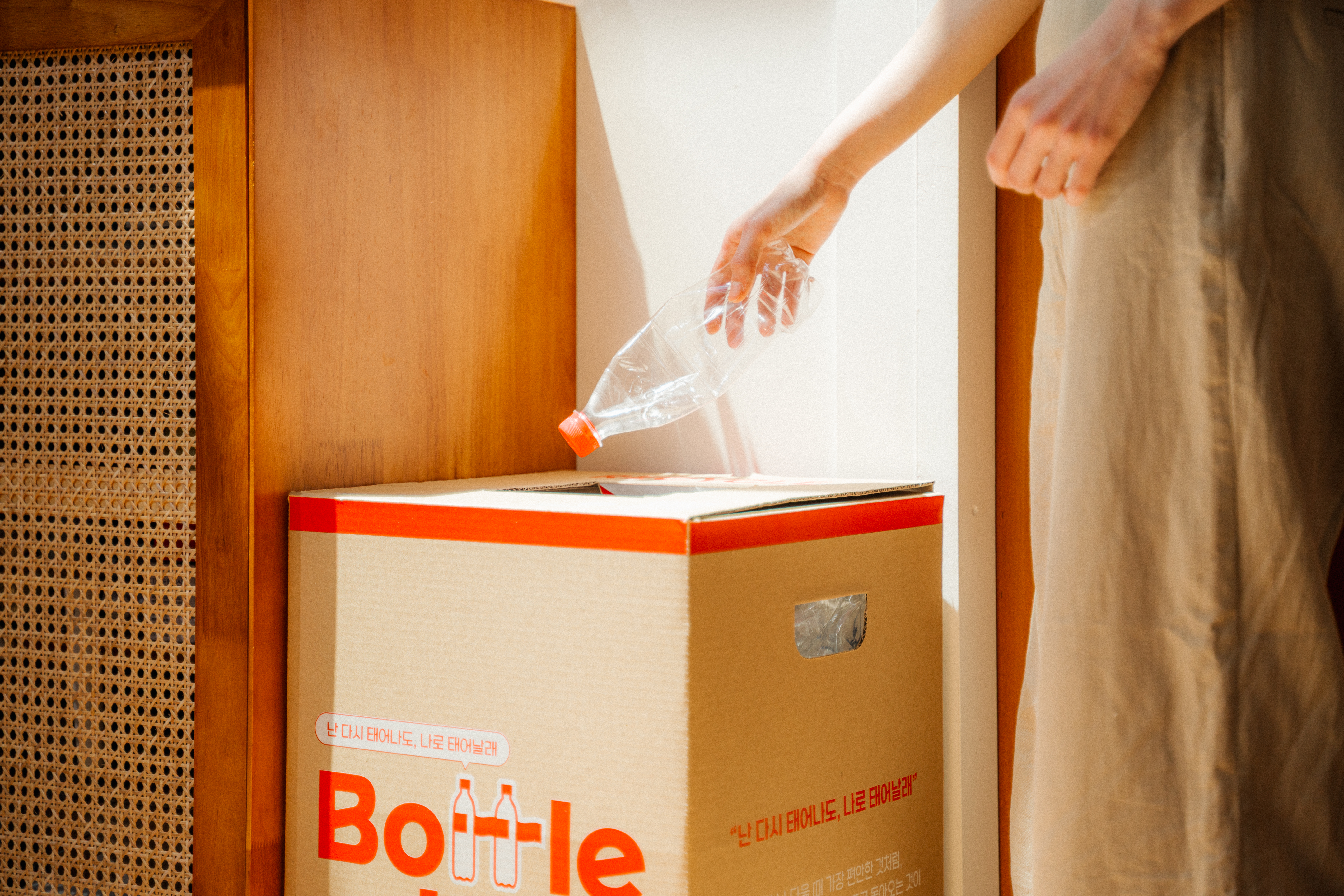 다 마신 후 깨끗이 헹구고 말린 코카-콜라 페트병을 제로 웨이스트 박스에 분리 배출하고 있는 모습