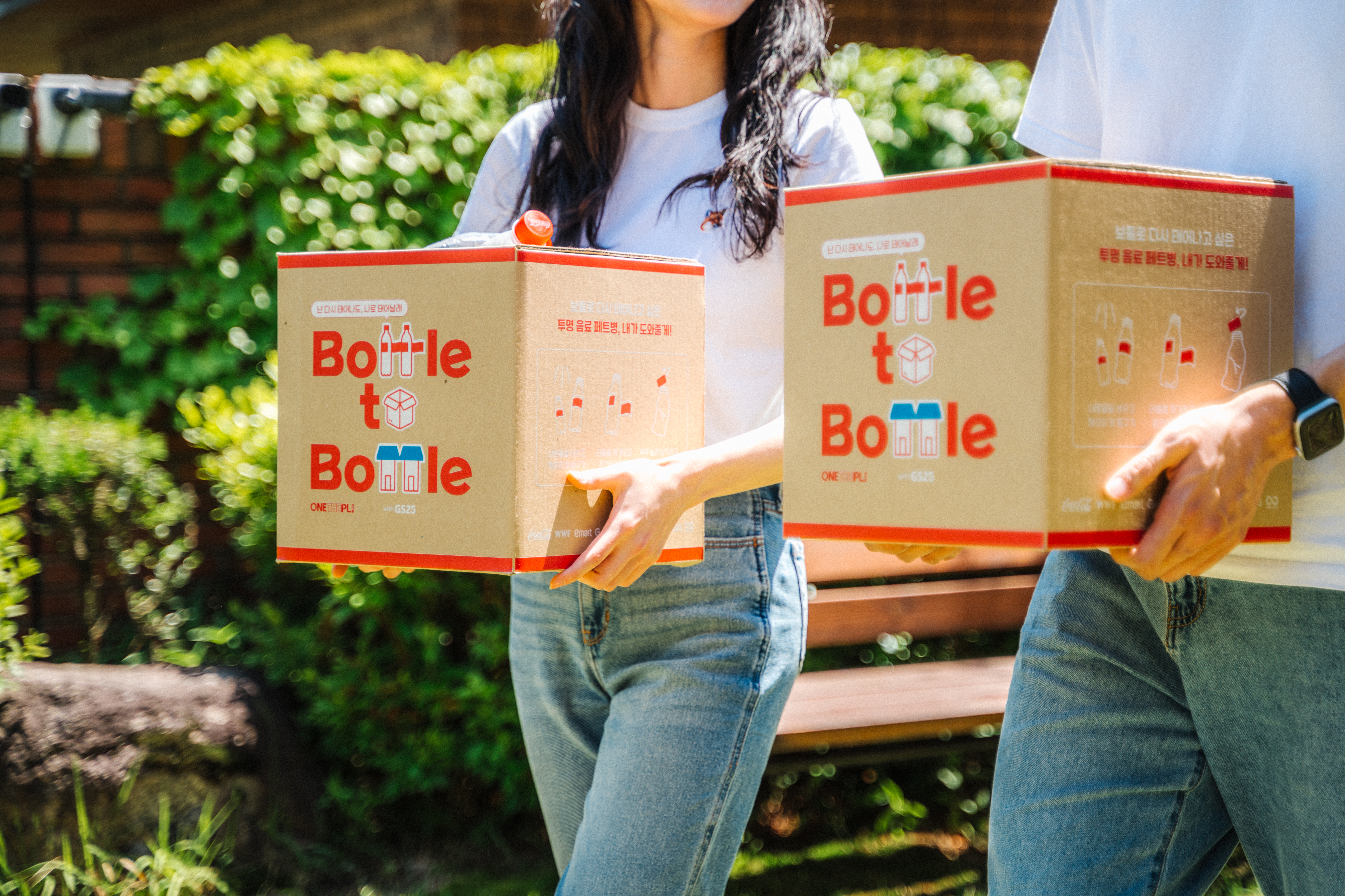 대학생 남녀가 투명 음료 페트병으로 꽉 채워진 제로 웨이스트 박스를 들고 걸어가는 모습