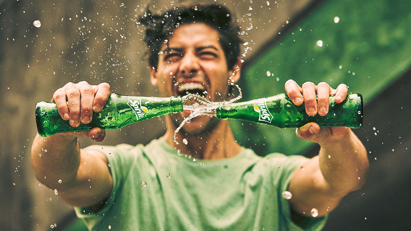 Dy shishe qelqi Sprite përplasen, duke spërkatur lëng të gazuar freskues.