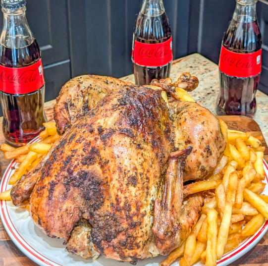 Pulë e pjekur me patate të skuqura dhe tre shishe Coca-Cola në sfond.