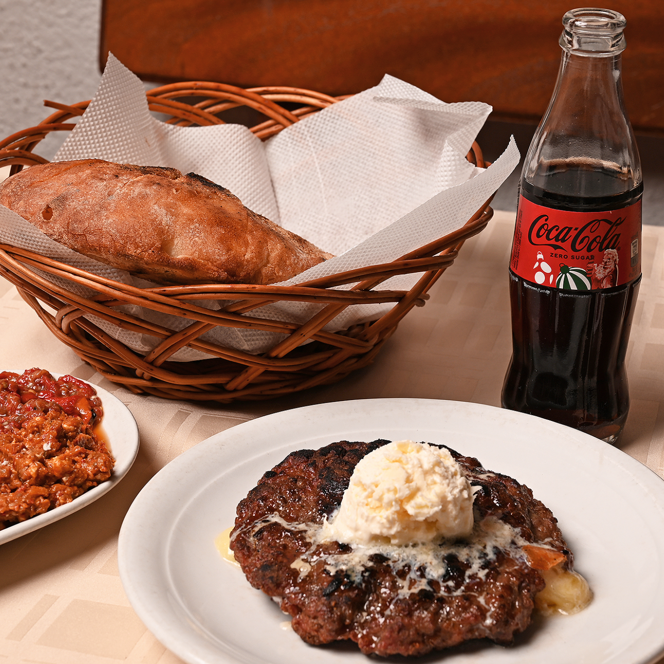 Pleskavicë me salcë të bardhë, bukë në kosh dhe Coca-Cola Zero.