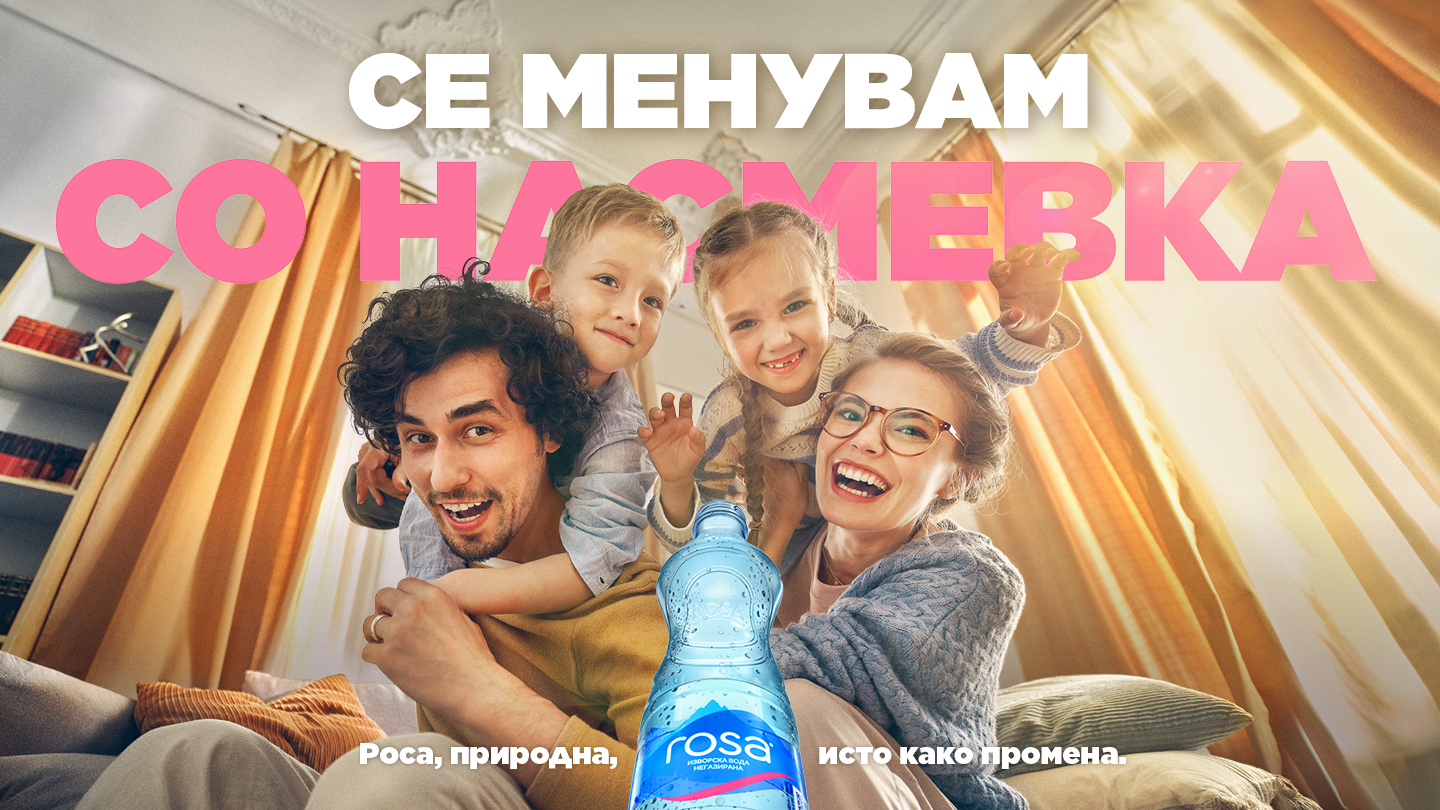 Shishe plastike uji Rosa me tekstin "Ndryshoj me një buzëqeshje" në një skenë shtëpiake me atmosferë familjare.