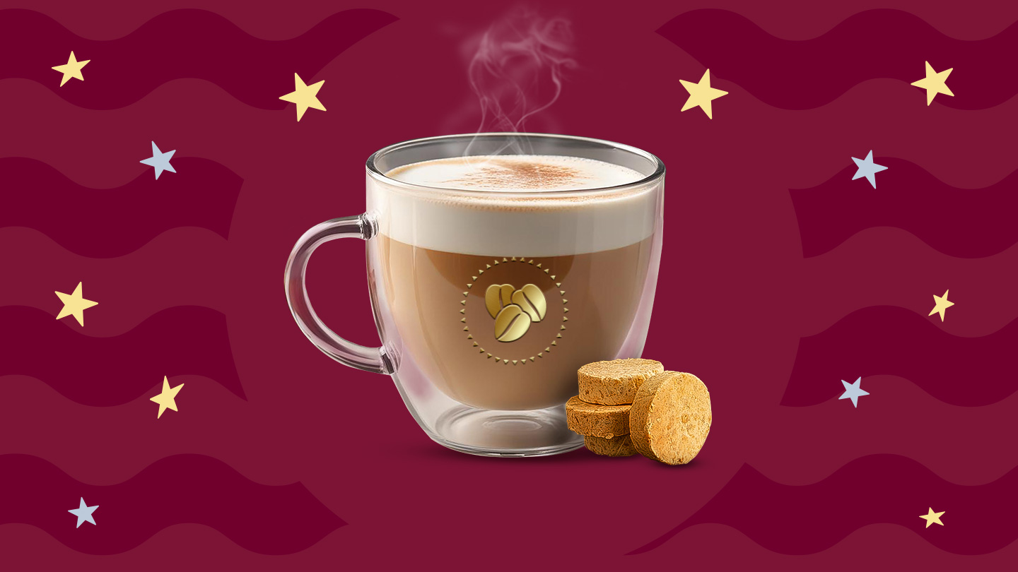 Una taza de cristal con café de mazapán caliente sobre un fondo en tonos guinda.