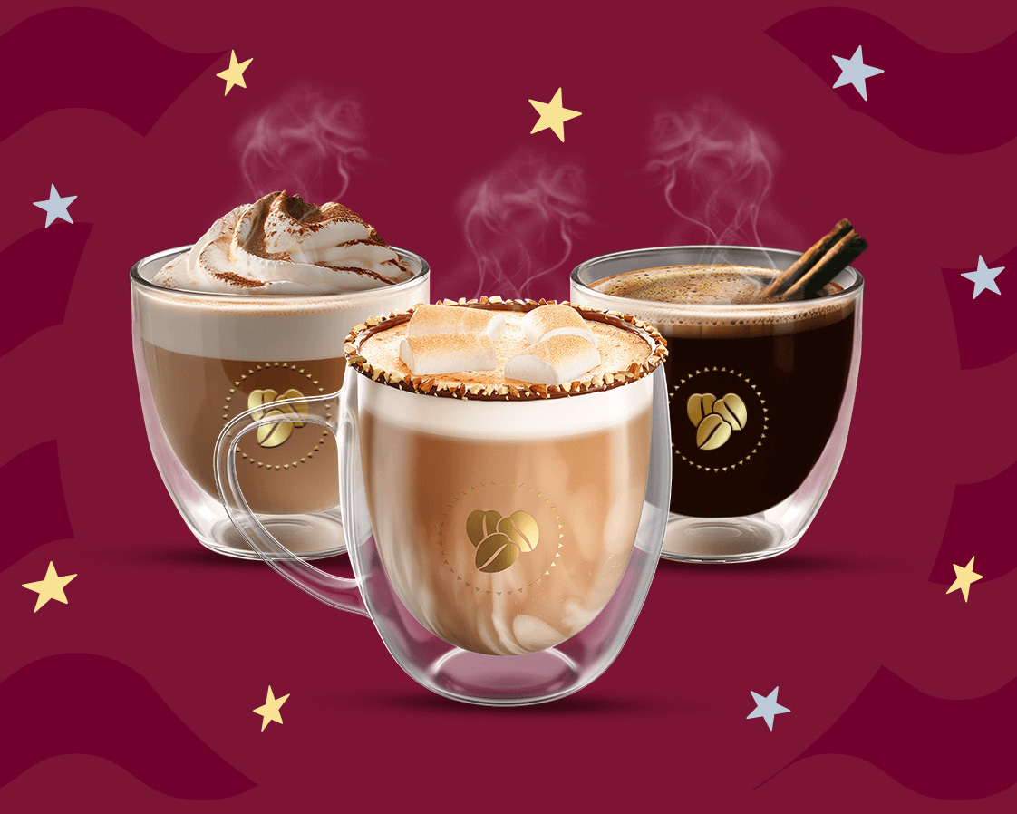 Tres tazas con distintos tipos de cafés calientes sobre un fondo de tonos guinda.