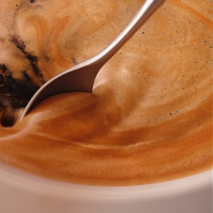 Cuchara revolviendo una taza con café americano.