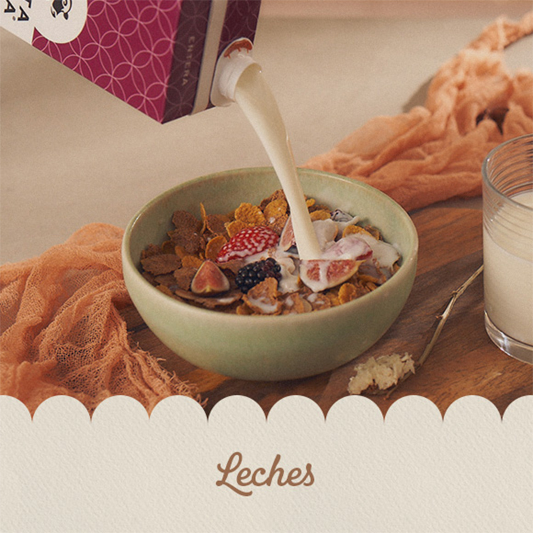 Imagen de un tazón con cereal y frutas, mientras se vierte leche desde un envase. A un lado, hay un vaso con leche sobre una tabla de madera.