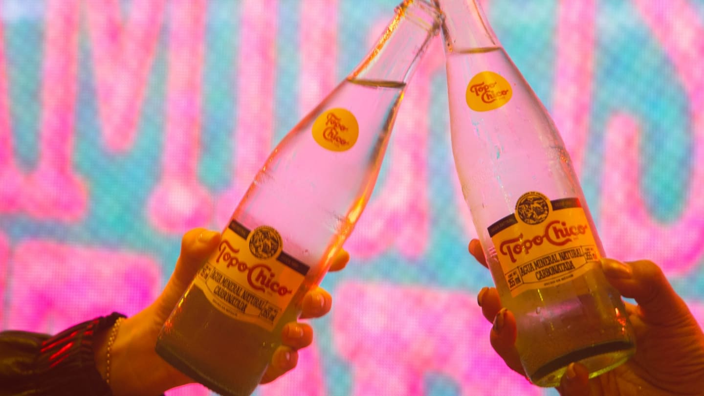Imagen de dos botellas de Topo Chico brindando