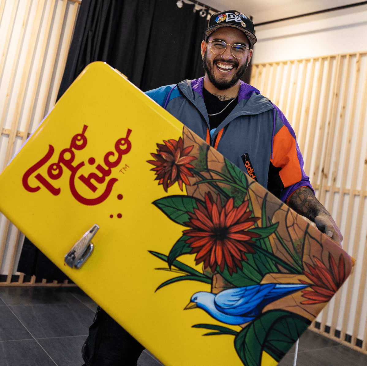 Mini Fridge Topo Chico con flores pintadas sostenida por una persona.