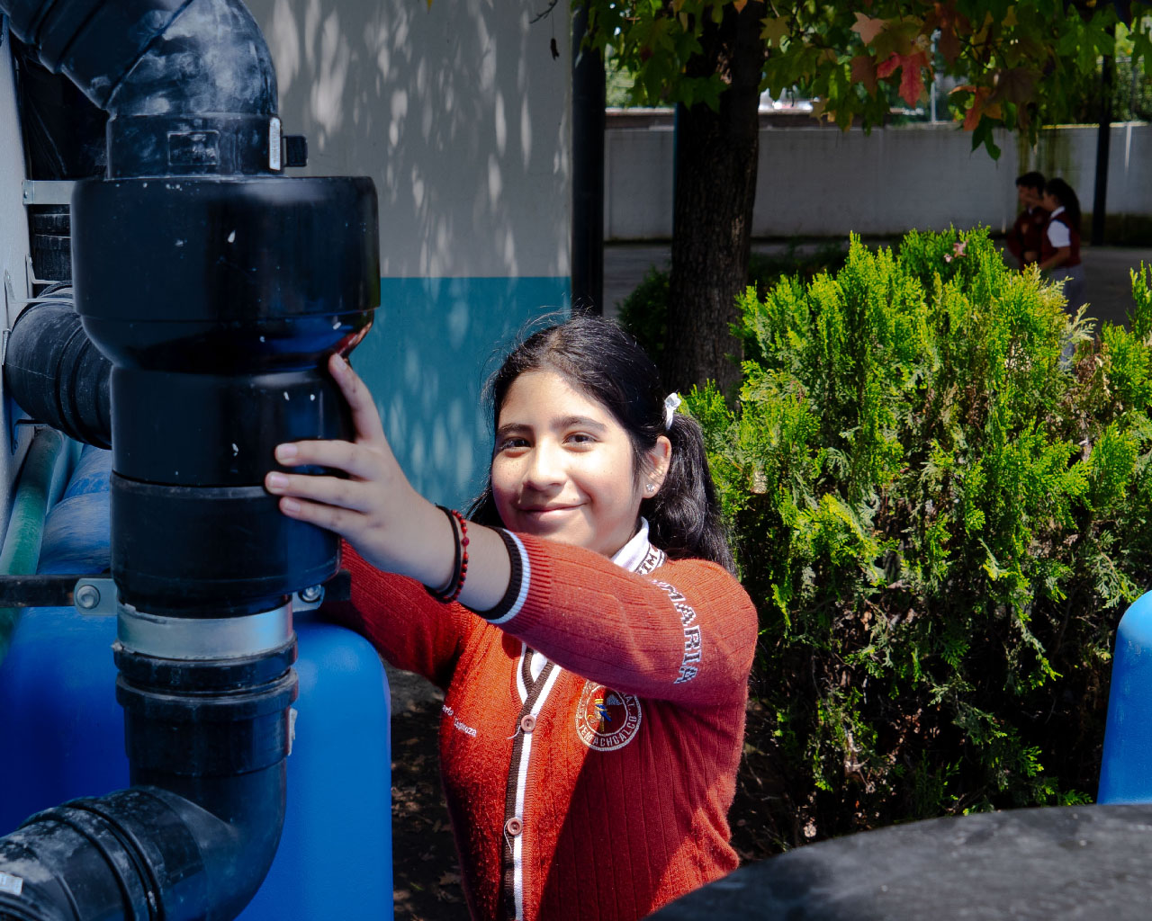 Niña sonriente abre una canilla.