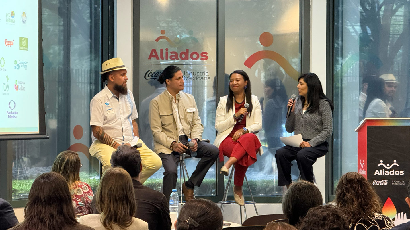 Una mesa redonda con cuatro ponentes y público, destacando logos de "Aliados", Coca-Cola y Fundación Televisa.
