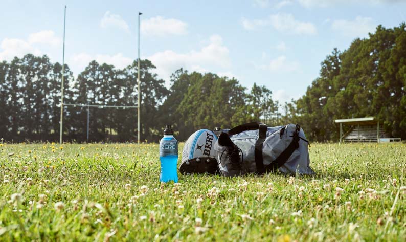 A bottle of Powerade on the ground of an empty rugby field