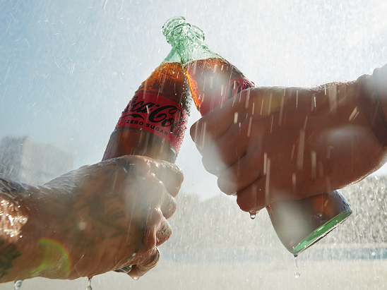 Detail of a person throwing a plastic bottle in Coca-Cola themed trash bin