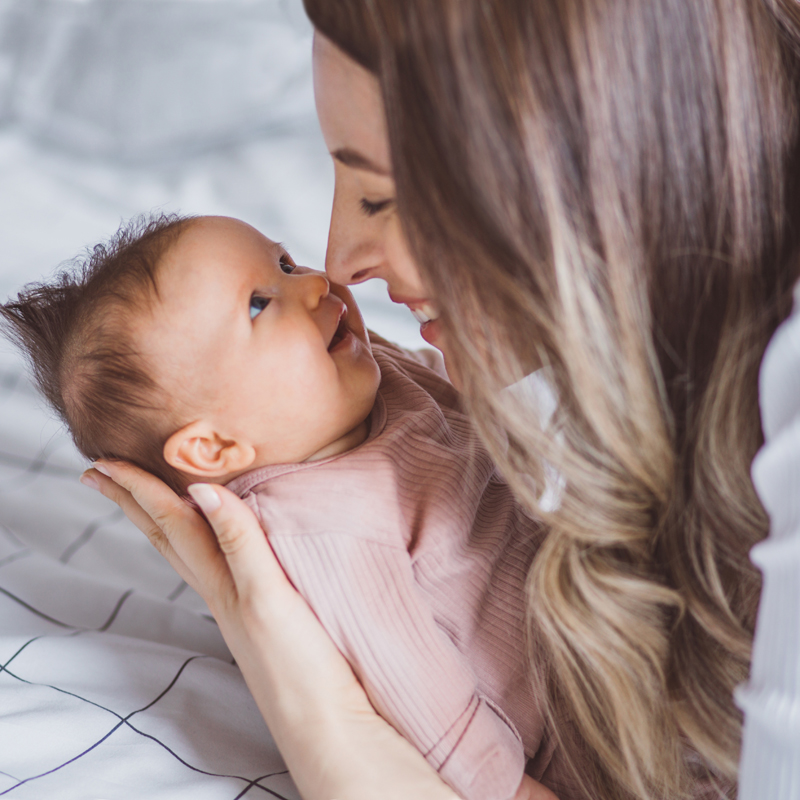 Osoba drži bebu umotanu u roze odeću i nežno je ljulja