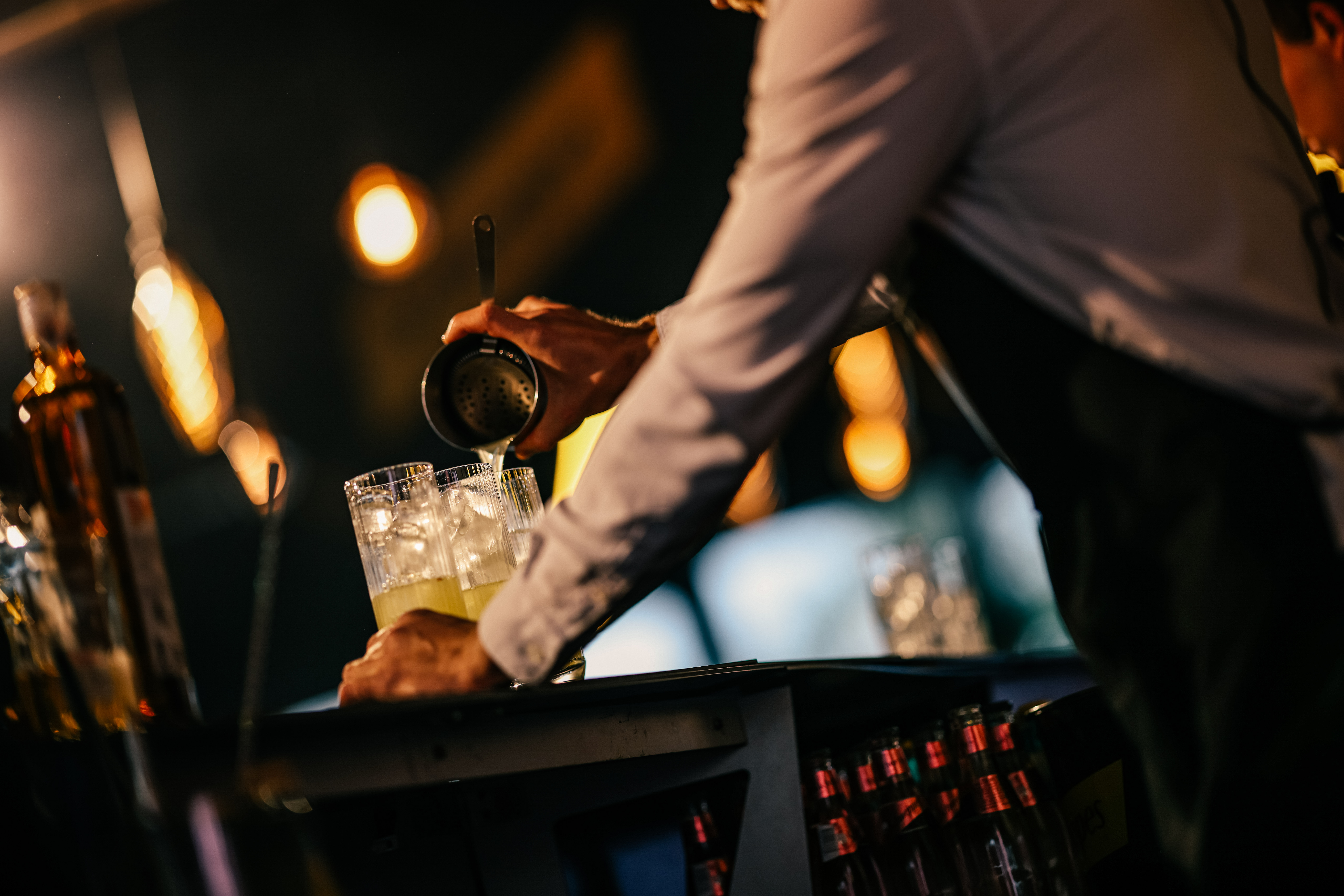 Barmen priprema koktel iza šanka uz tekst promocije takmičenja Schweppes Mixology Session 2025