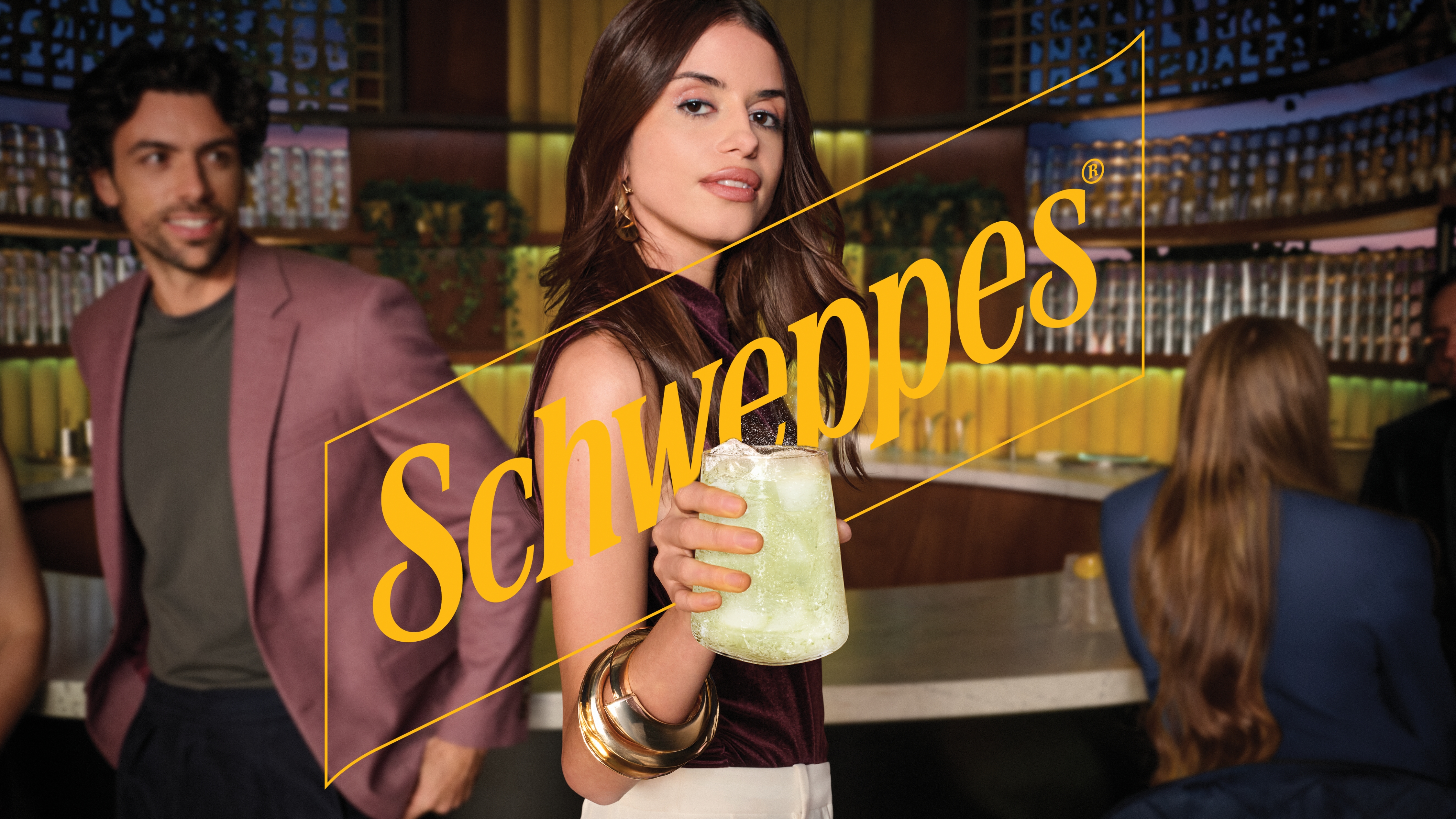 Skupina ljudi se zabava z napitki Schweppes.