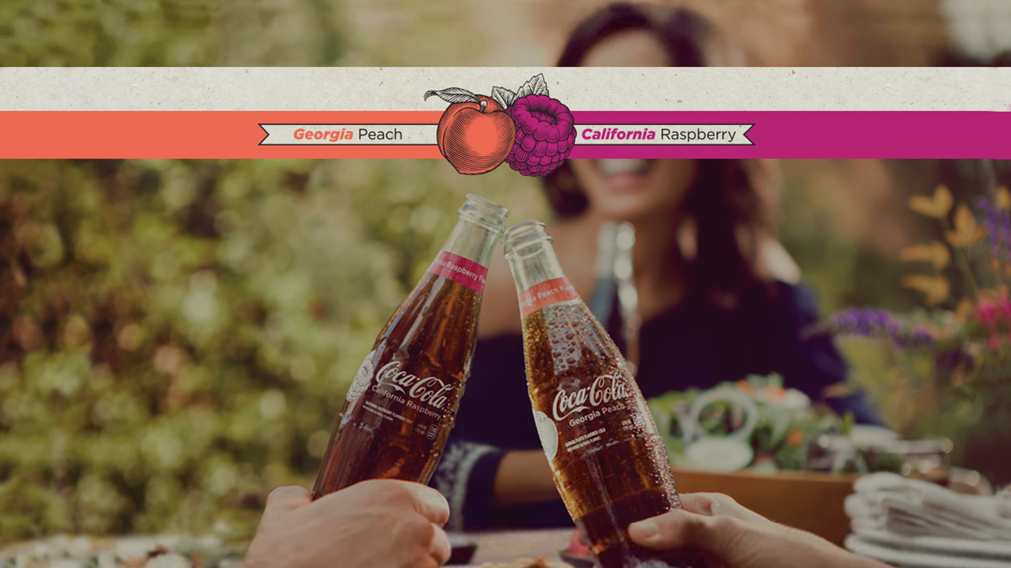 Detail of two hands toasting with Coca-Cola Local Flavors bottles while a woman smile on the background