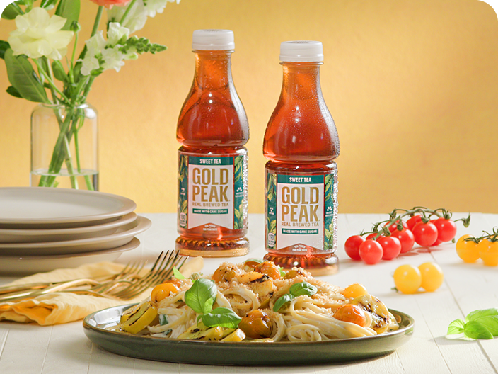 a bottle of gold peak tea next to tamales and green onions