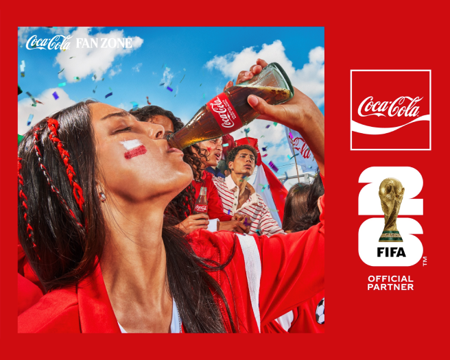Fans in red celebrating at Coca-Cola FIFA Fan Zone, woman raising a Coke bottle amid confetti and FIFA World Cup branding.